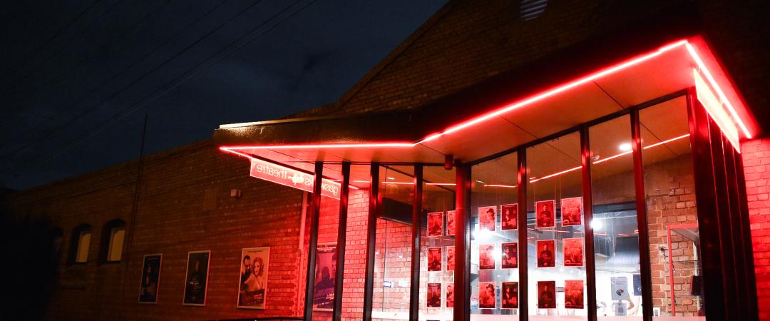 Main entrance to Gasworks Theatre at night, in a glow of red light. 